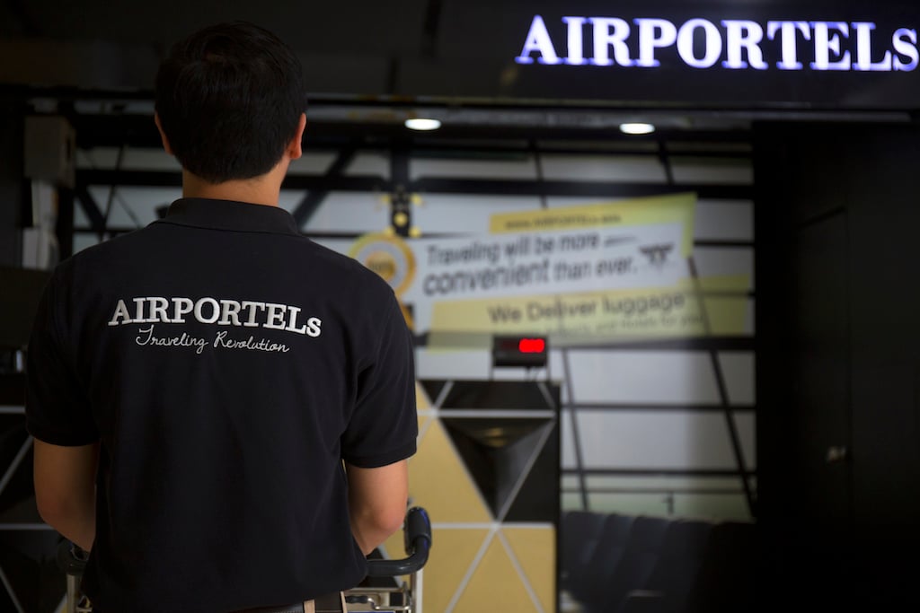 AIRPORTELsのロゴが入ったポロシャツのスタッフが、AIRPORTELsのカウンターの前に立っている